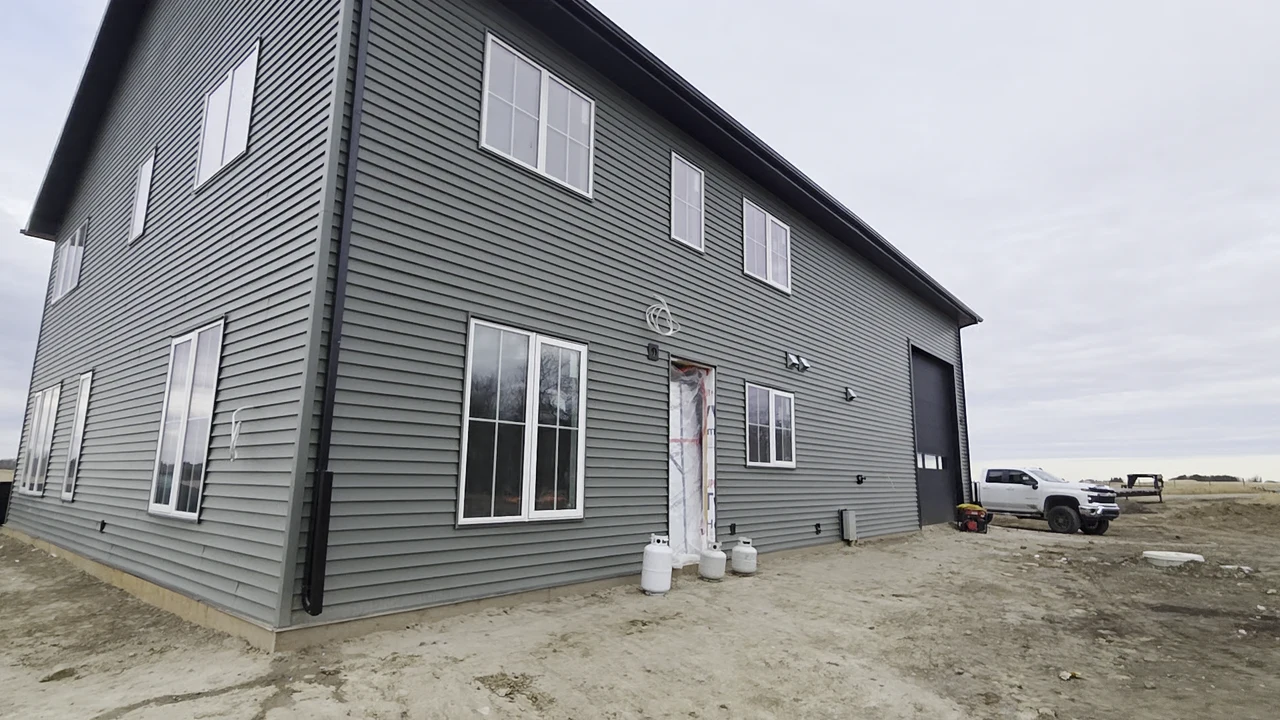 Grey-sided workshop with white window trim and dark downpipes