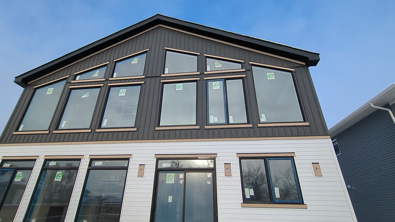 White lap siding and dark vertical accents around a large rear window wall during home construction