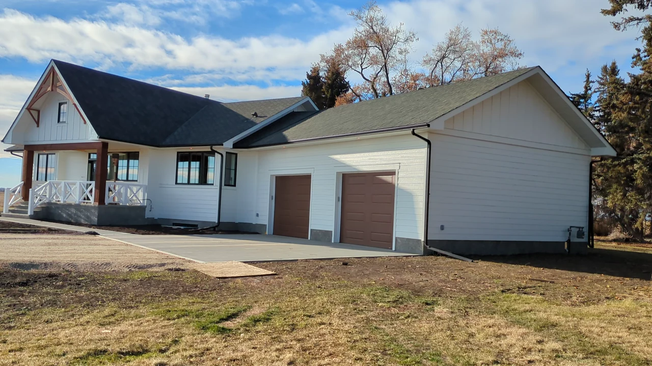 White-sided home with a covered porch, brown garage doors and dark roofline details