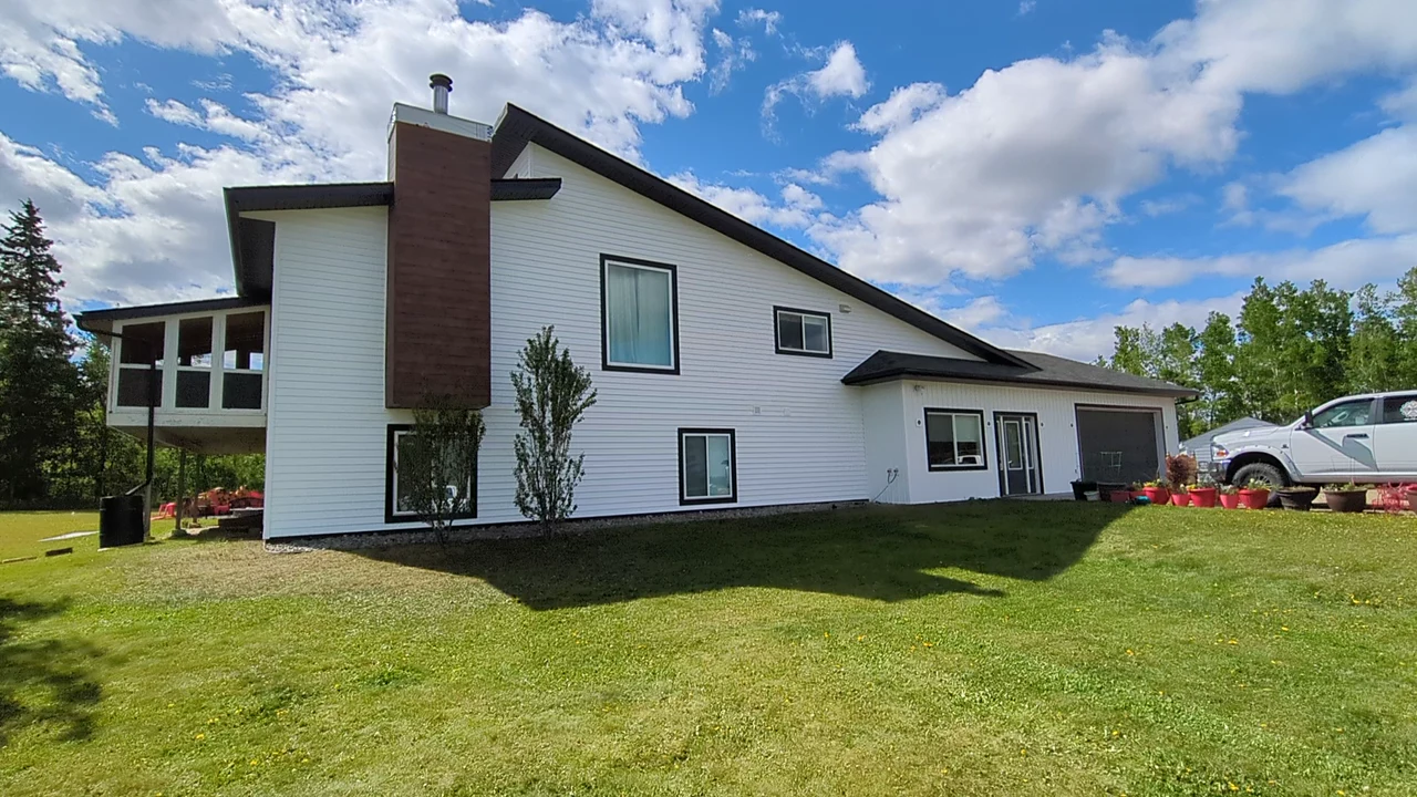 White split-level home with dark window trim and a brick chimney