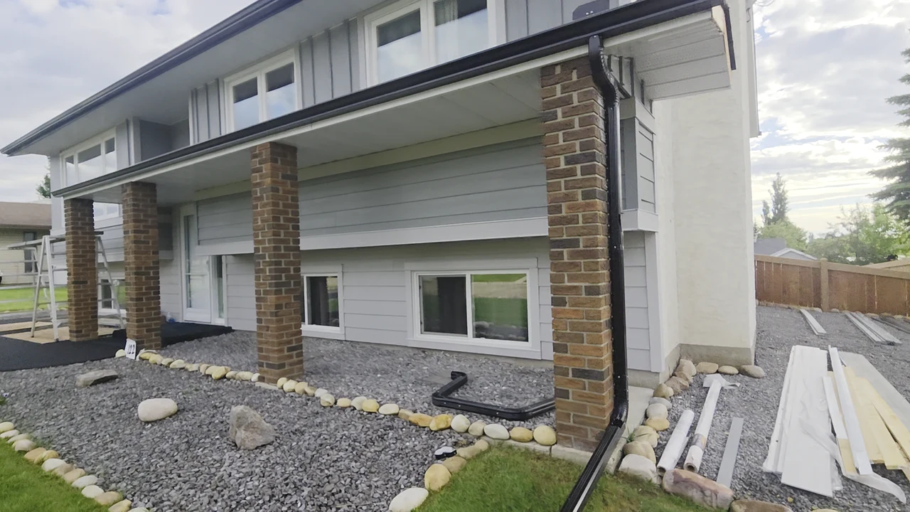 Grey lap siding and vertical upper accents with white window trim and brick columns