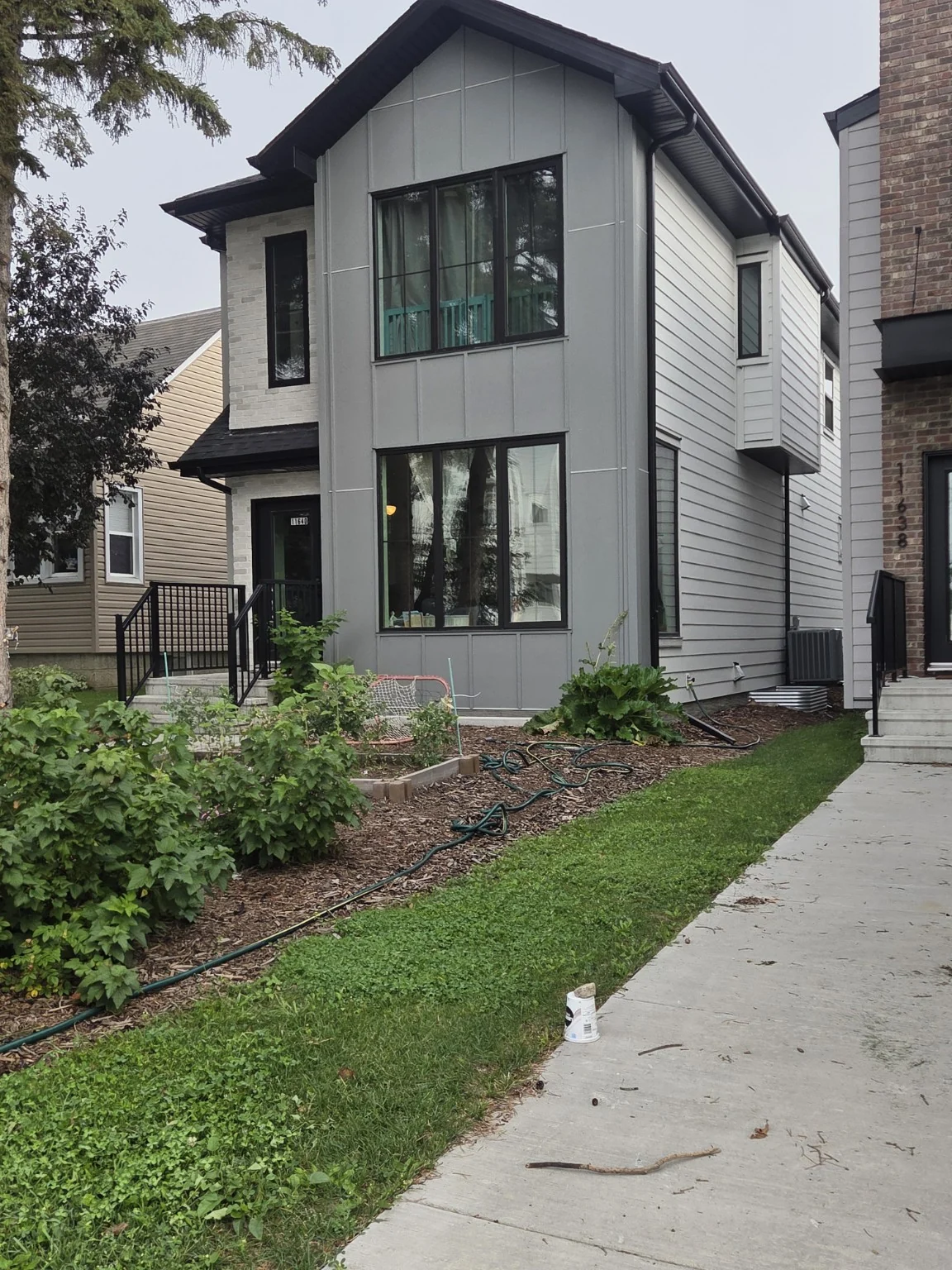 Grey panel and lap siding with dark window trim on a narrow two-storey home