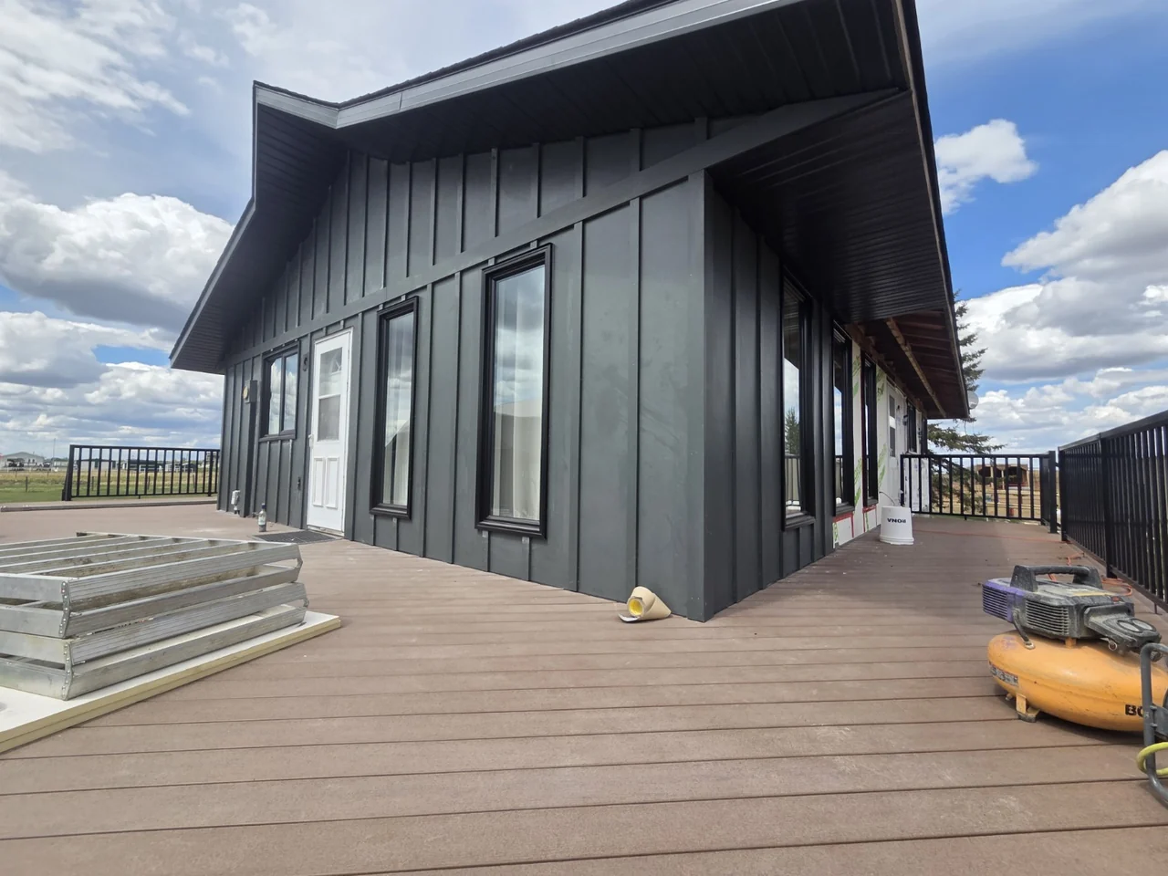 Board-and-batten siding installation in progress beside the deck