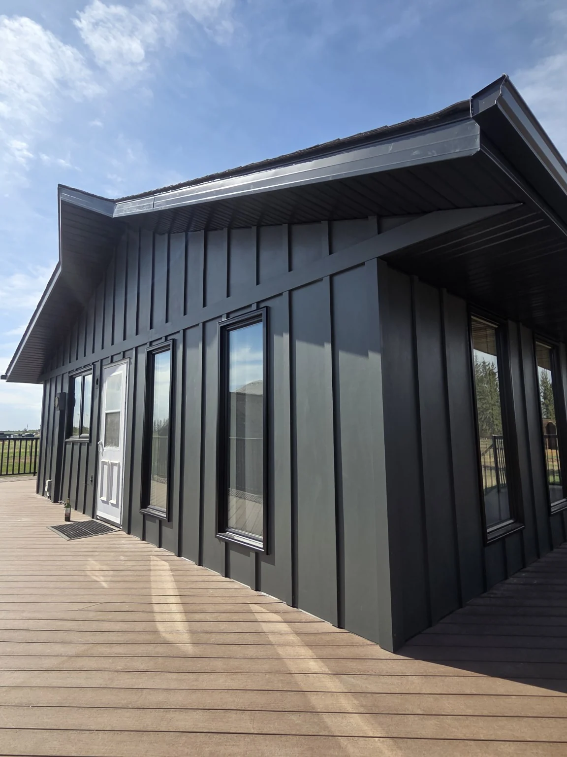 Charcoal Hardie board-and-batten siding and coordinated dark soffit on a Front-Line renovation