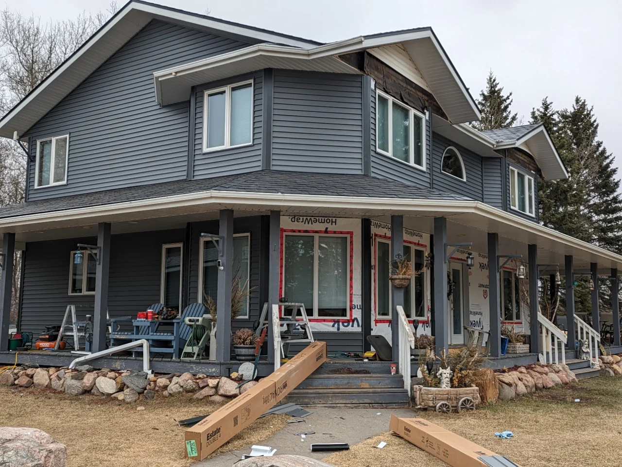 Charcoal vinyl renovation in progress with exposed house wrap and unfinished gable areas