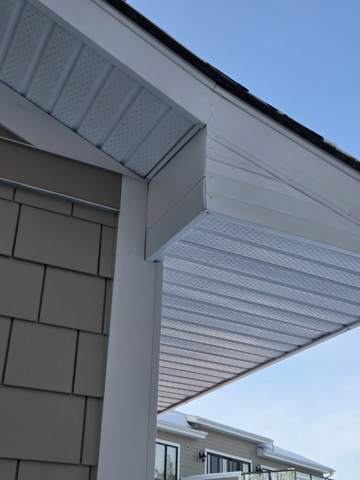 White soffit and fascia at a roof return beside shingle-style siding