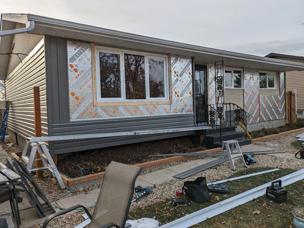 Insulation and preparation over existing stucco with vinyl siding installation underway